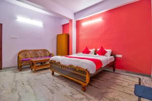 1 dormitorio con cama y pared roja en OYO Atithi Bhawan, en Jamshedpur