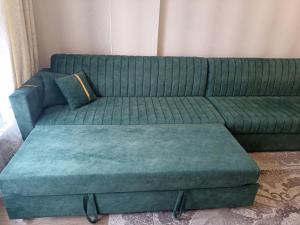 ein grünes Sofa mit einer Ottomane im Wohnzimmer in der Unterkunft Orion Apartment in Bischkek