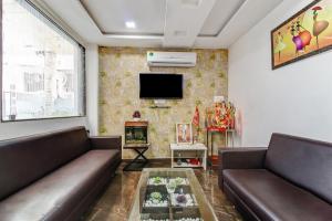 a living room with two brown couches and a tv at Townhouse Soni Inn in Rāipur