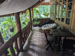 un porche de una casa de madera con mesa y sillas en Baanmai Phaipa House, en Sai Yok