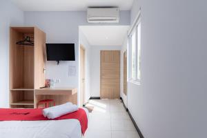 a hotel room with a bed and a tv at RedDoorz near Puri Indah Lippo Mall 2 in Jakarta