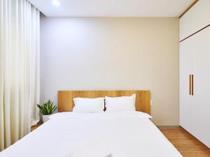 Schlafzimmer mit einem großen weißen Bett mit einem Kopfteil aus Holz in der Unterkunft 2 Bedrooms City View The Gold View in Ho-Chi-Minh-Stadt