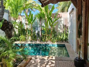 a swimming pool in the middle of a courtyard with palm trees at Jawa House Private Villas in Gili Trawangan