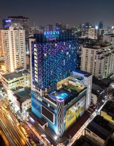 um edifício com luzes acesas numa cidade à noite em VELA Dhi GLOW Pratunam em Bangkok