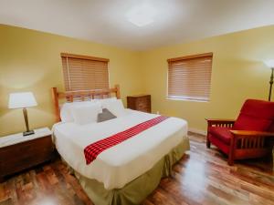 a bedroom with a large bed and a red chair at Crooked River Ranch Cabins in Terrebonne