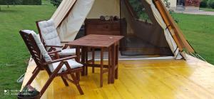 a wooden table and two chairs next to a tent at Na vrtu K25 in Gradac