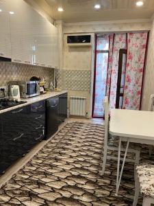 eine Küche mit einer Theke, einem Tisch, einem Tisch und Stühlen in der Unterkunft Orion Apartment in Bischkek