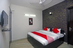ein Schlafzimmer mit einem großen Bett mit roten Kissen in der Unterkunft OYO Maira Stays in Indraprast