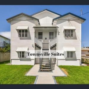 una casa blanca con las palabras suites del pueblo en ella en Townsville Suites, en Townsville