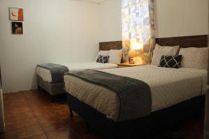 1 dormitorio con 2 camas y 1 silla en Real Hostal, en Guatemala