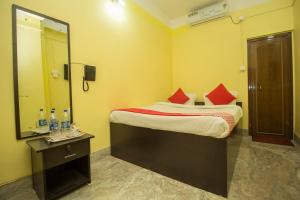 Schlafzimmer mit einem Bett mit roten Kissen und einem Spiegel in der Unterkunft OYO Hotel Kshounish Residency in Māldah