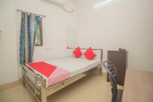 małe łóżko z czerwonymi poduszkami w pokoju w obiekcie OYO Hotel Kshounish Residency w mieście Māldah