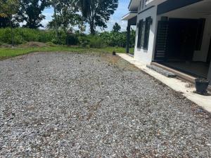 a gravel driveway in front of a house at Aimy’s Homestay in Simpang Empat