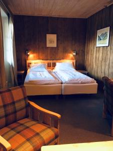 2 Betten in einem Zimmer mit einem Stuhl und einem Sofa in der Unterkunft Fossheim Hotel Lom in Lom