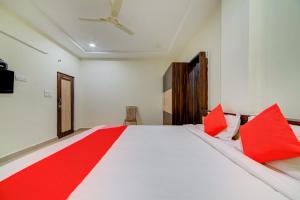 a bedroom with a large white bed with red pillows at OYO KSL Guest House in Karīmnagar