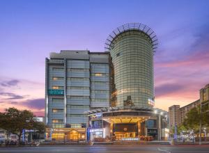 a large building with a glass facade in a city at Dijon Hotel Shanghai in Shanghai