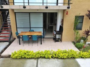 une terrasse avec une table et des chaises en bois devant une maison dans l'établissement hermoso apartamento amoblado, à La Tebaida