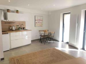 a kitchen with white cabinets and a table with chairs at Magnifique studio indépendant 35m2 proche du lac et au coeur du village in Peyrolles-en-Provence