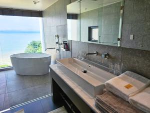 a bathroom with a tub and a large mirror at Beach front studio -NagoNago- in Nago