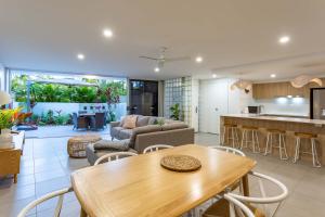 Il dispose d'une cuisine et d'un salon avec une table et des chaises en bois. dans l'établissement BEACHFRONT BLISS POSITIONED PERFECTLY IN COTTON TREE, à Maroochydore