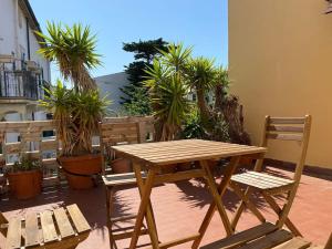 a wooden table and chairs on a patio with palm trees at Terraced House near the Sea in Livorno
