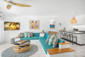 uma sala de estar com um sofá azul e uma cozinha em Belle Escapes Sapphire Suite Oceanview 17 Alamanda Palm Cove em Palm Cove