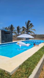 a pool with an umbrella and an inflatable at Tres Velas Surf in Celestino Gasca