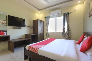 a bedroom with a bed and a tv and a window at Summer Palms in Kangra