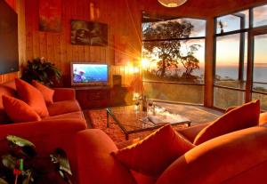sala de estar con sofás naranjas y TV en Summit Views Skyview Penthouse, en Arthurs Seat