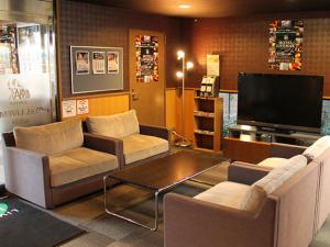 a living room with couches and a flat screen tv at HOTEL LiVEMAX BUDGET名古屋 in Nagoya