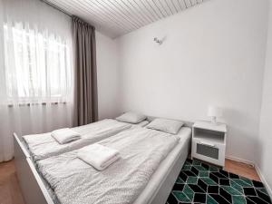 a white bedroom with a bed and a window at Summer House in Lubniewice