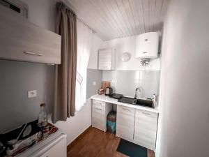 a small kitchen with white cabinets and a sink at Summer House in Lubniewice