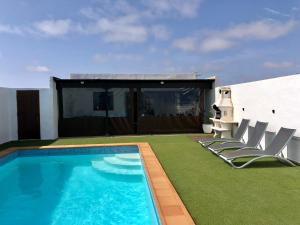 a swimming pool with chairs next to a house at Villa Miriam in Tinajo