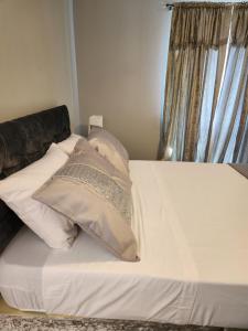 ein Bett mit weißer Bettwäsche und Kissen darauf in der Unterkunft 4 Goodman Lodge & 7 goodman Lodge in Thornton Heath