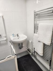 a white bathroom with a sink and a towel rack at 4 Goodman Lodge & 7 goodman Lodge in Thornton Heath