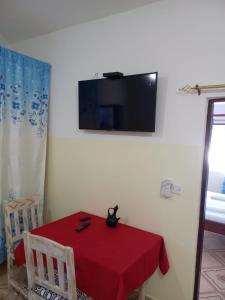 a room with a red table with a tv on the wall at Rhino Apartment Watamu in Watamu