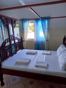a bedroom with a large bed with blue curtains at Rhino Apartment Watamu in Watamu