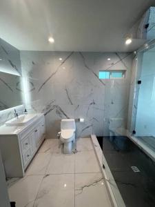 La salle de bains blanche est pourvue de toilettes et d'un lavabo. dans l'établissement Hummingbird Oceanfront Cottage, à Hauula