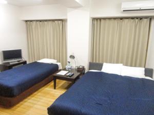 a hotel room with two beds and a television at HOTEL LiVEMAX BUDGET名古屋 in Nagoya