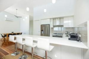 een witte keuken met een aanrecht en witte stoelen bij Executive Accommodation Absolute Beach Front in Middleton