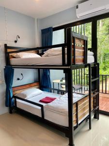 two bunk beds in a room with a window at Boom Hostel Khao Sok in Khao Sok