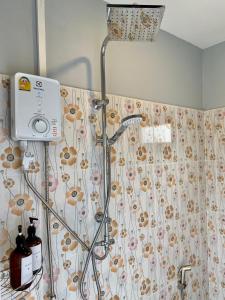 a shower in a bathroom with a floral shower curtain at Boom Hostel Khao Sok in Khao Sok