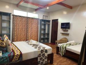 ein Hotelzimmer mit 2 Betten und einem TV in der Unterkunft MANANQUIL TRAVEL LODGE in El Nido