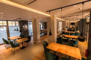 a restaurant with wooden tables and green chairs at Hotel Arka in Orşova