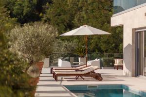 - une piscine avec 2 chaises longues et un parasol dans l'établissement Villa Roc Blanc, à Tivat