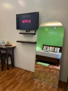 Habitación con cama, TV y mesa. en MANANQUIL TRAVEL LODGE en El Nido