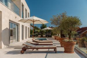 une rangée de bancs avec un parasol et une piscine dans l'établissement Villa Roc Blanc, à Tivat