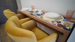 a table with two yellow chairs and a table with plates on it at President 034 Royal Spa in Arandelovac
