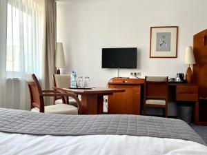 een hotelkamer met een slaapkamer met een bureau en een bed bij City Hotel in Bydgoszcz