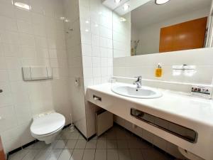 a white bathroom with a toilet and a sink at City Hotel in Bydgoszcz